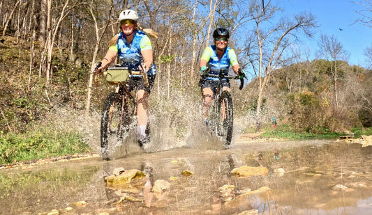 Two Dirt Squad riders crossing a shallow creek at fall camp